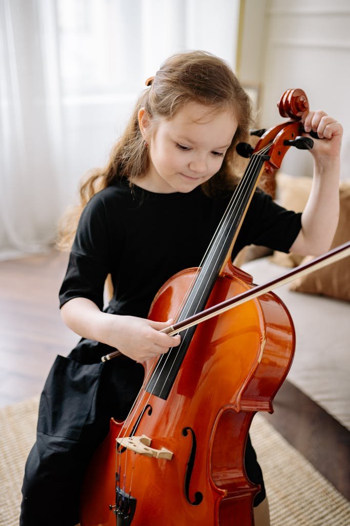 A young girl practicing cello indoors, showcasing musical talent and concentration. Gilgamesh Academy